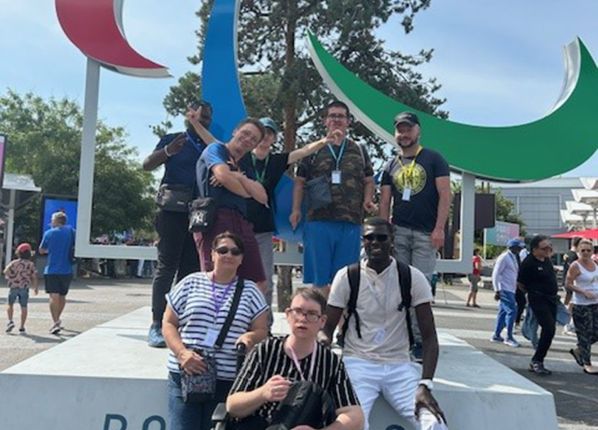 Photo de jeunes en situation Handicap devant. le logo des Jeux Paralympiques au JO de Paris en 2025 avec les PEP18