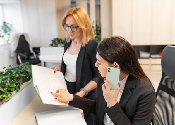 2 femmes derrières un bureau dont l'une est au tel
